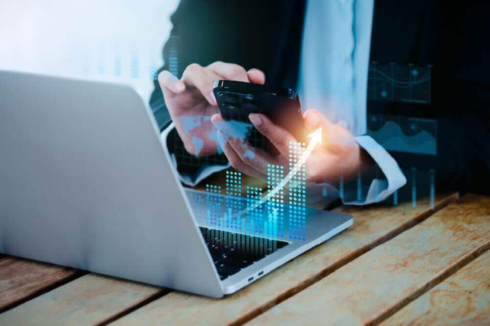 Business professional analyzing financial growth on laptop and phone