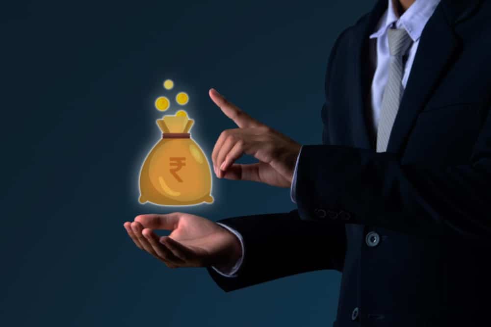 Businessman pointing at money bag icon symbolizing wealth growth