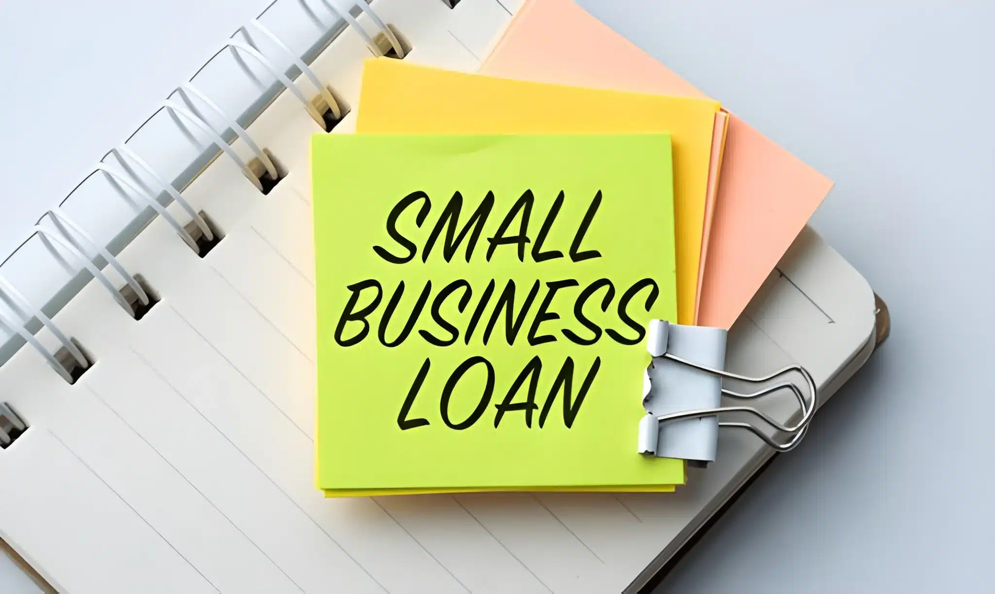 A yellow and orange sticky note with the word small business loan written on it