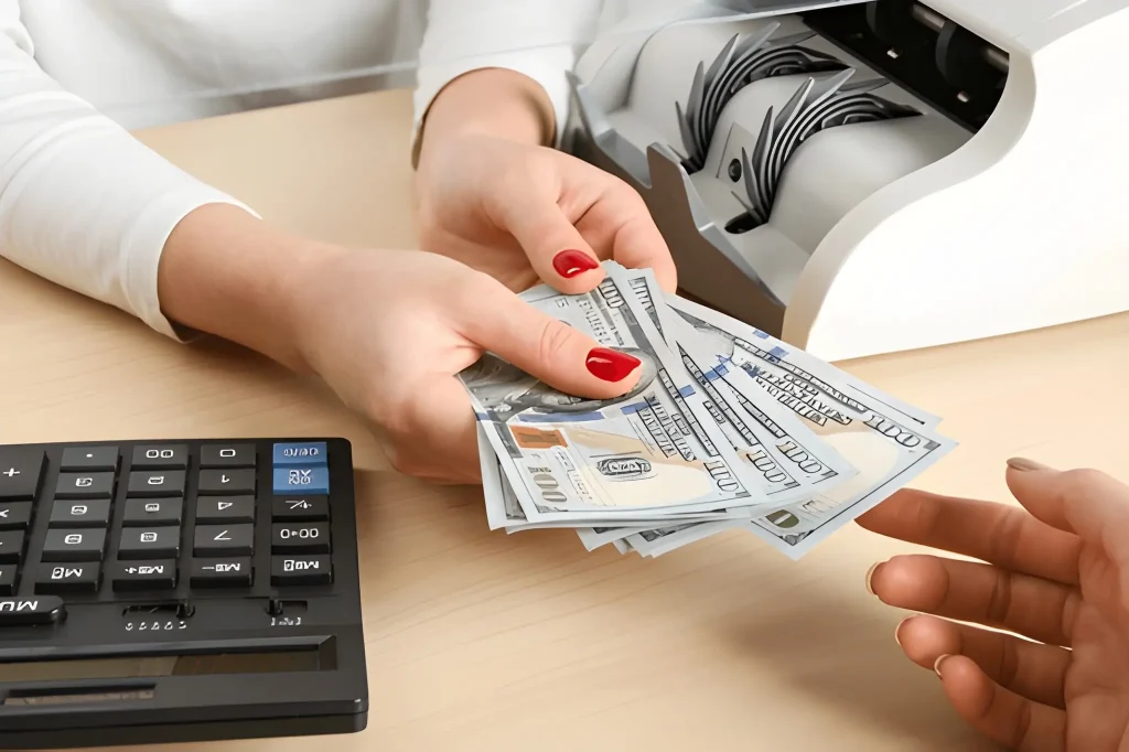 Cashier giving dollar banknotes to client at table in money exchange