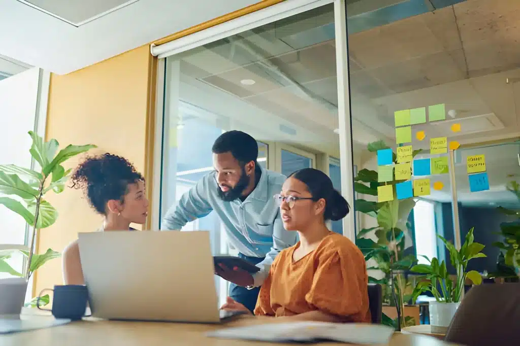 Three diverse professional women in business attire smiling and posing in an office
