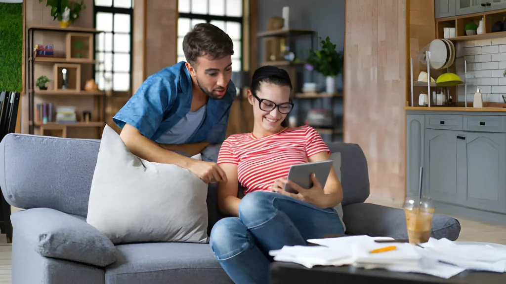 Couple calculating bills at home using tablet and calculator