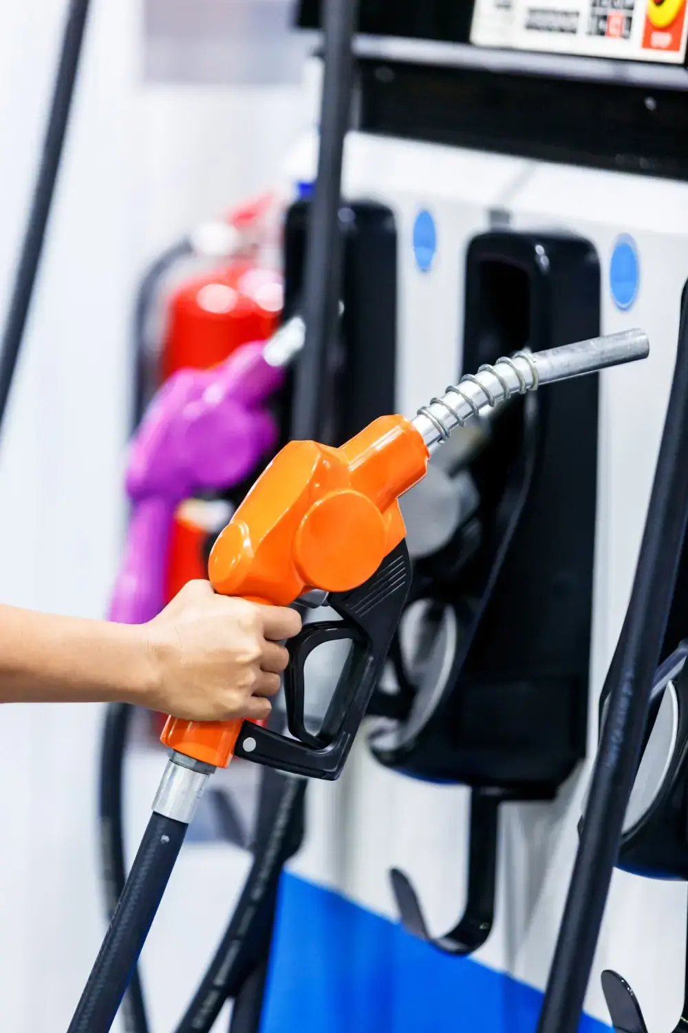 Close-up hand holding fuel nozzle at a gas station
