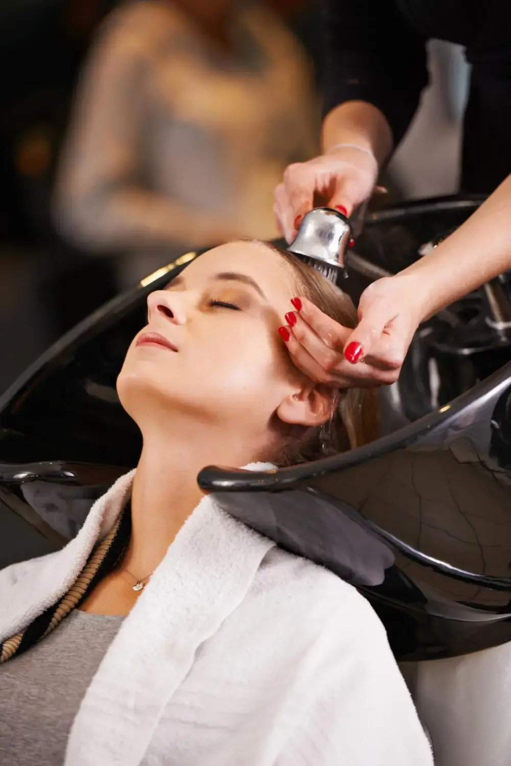 Woman receiving a professional hair wash and scalp treatment at a beauty salon.